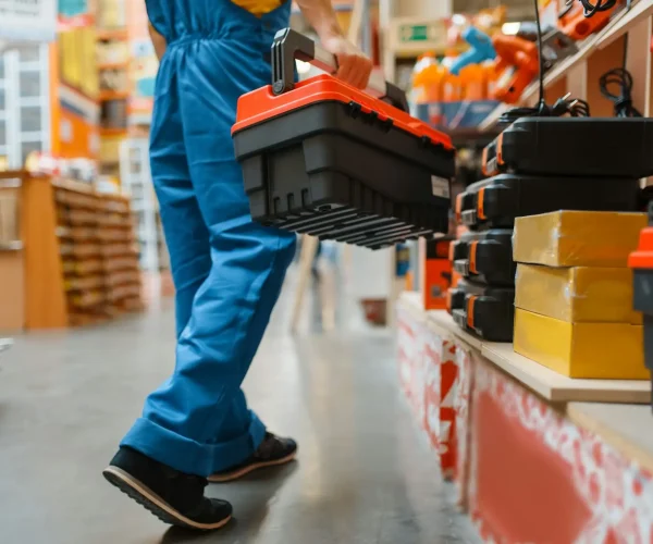Builder with toolbox at the shelf, hardware store